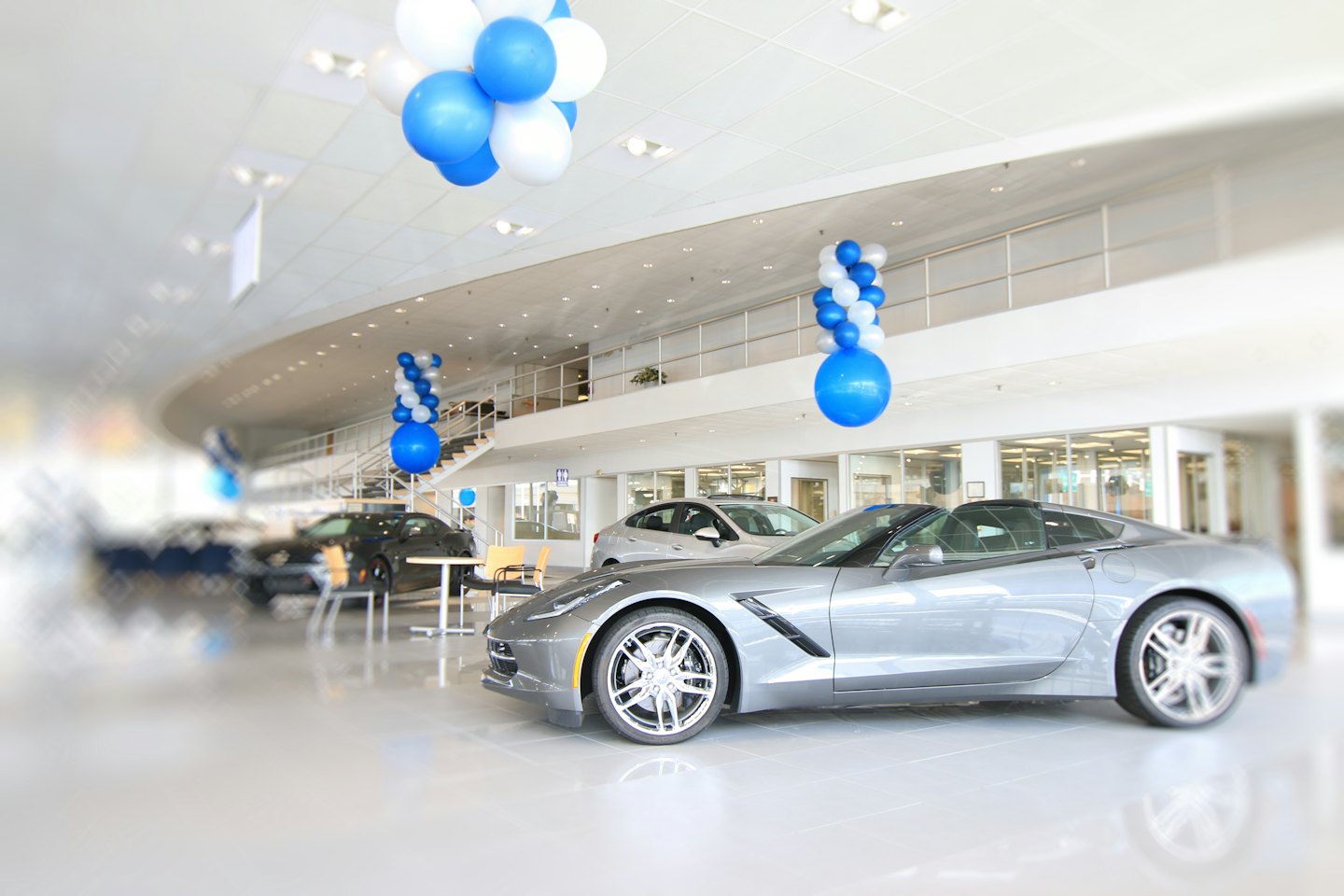 Shiny grey sports car in a modern car dealership showroom.